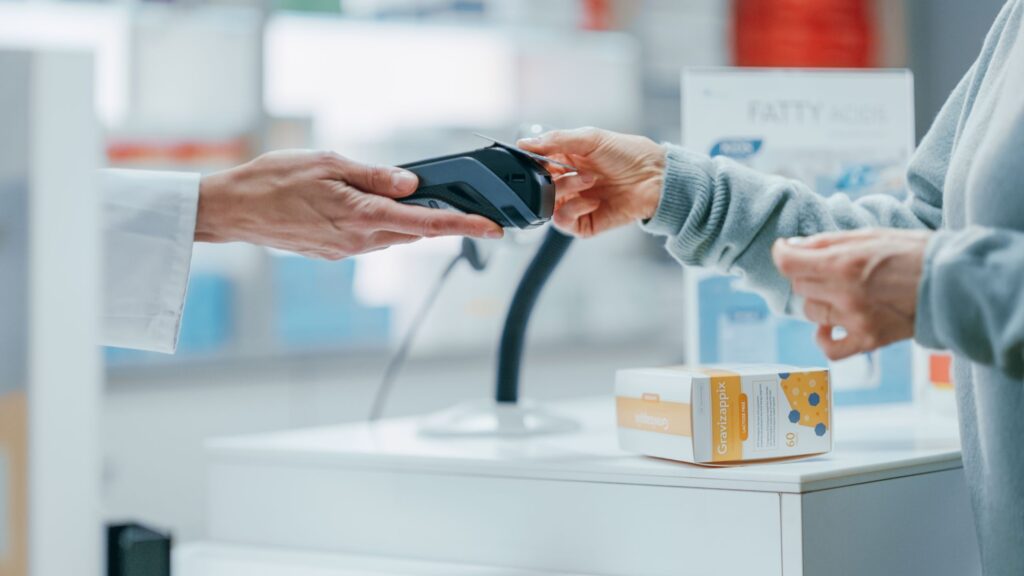 A young woman making a contactless payment at a pharmacy.