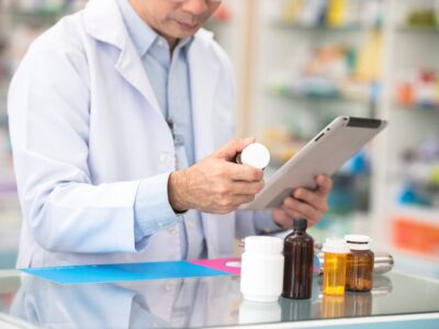 Male pharmacist looking at a tablet and prescription.