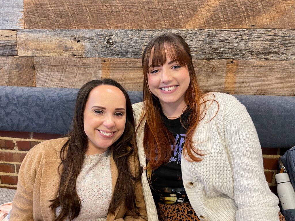 Two women smiling while sitting.