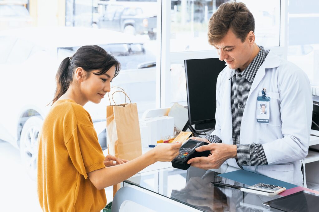 A woman using a credit card to pay at a pharmacy.