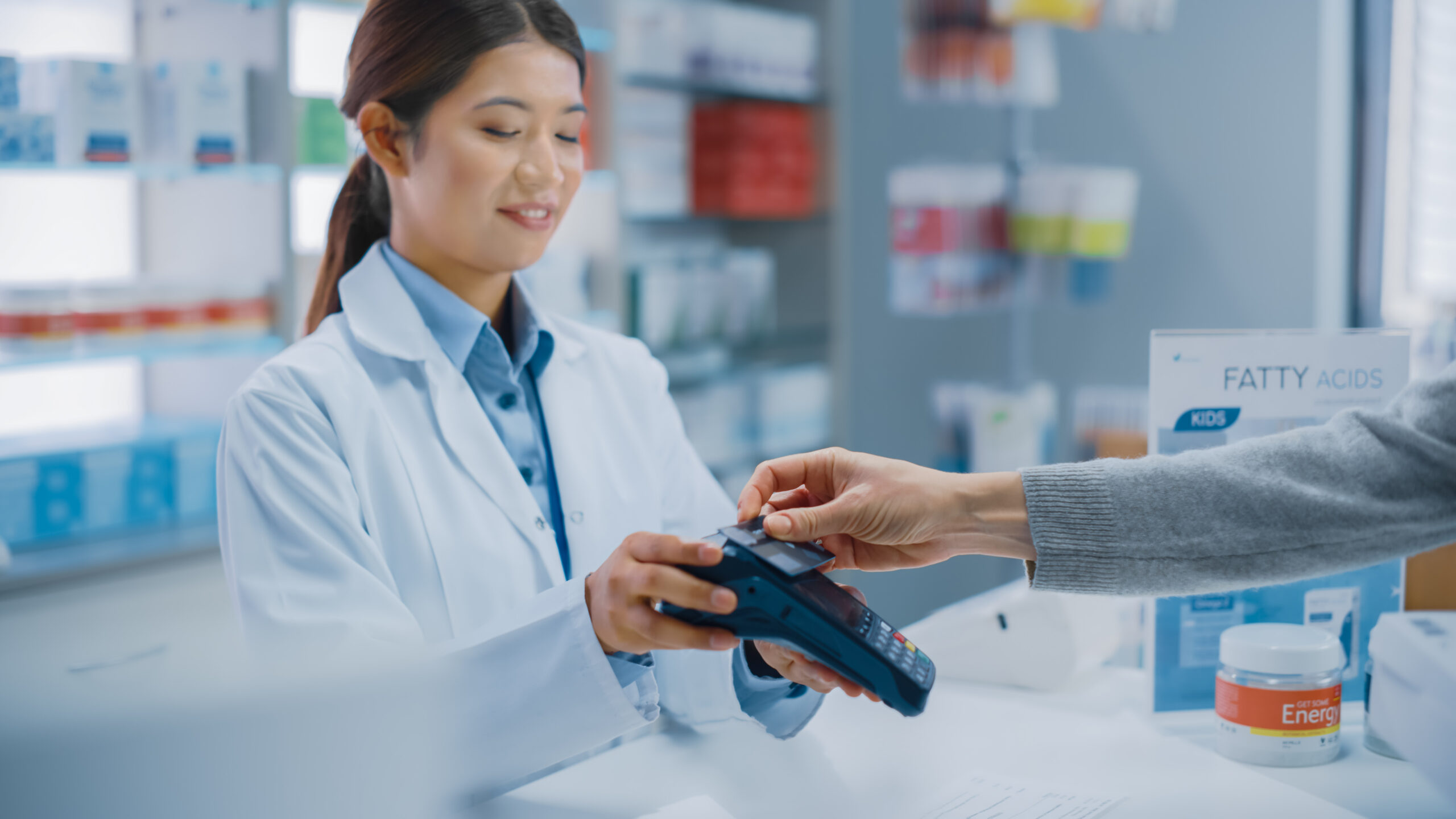 A female pharmacist taking a contactless payment from a customer.