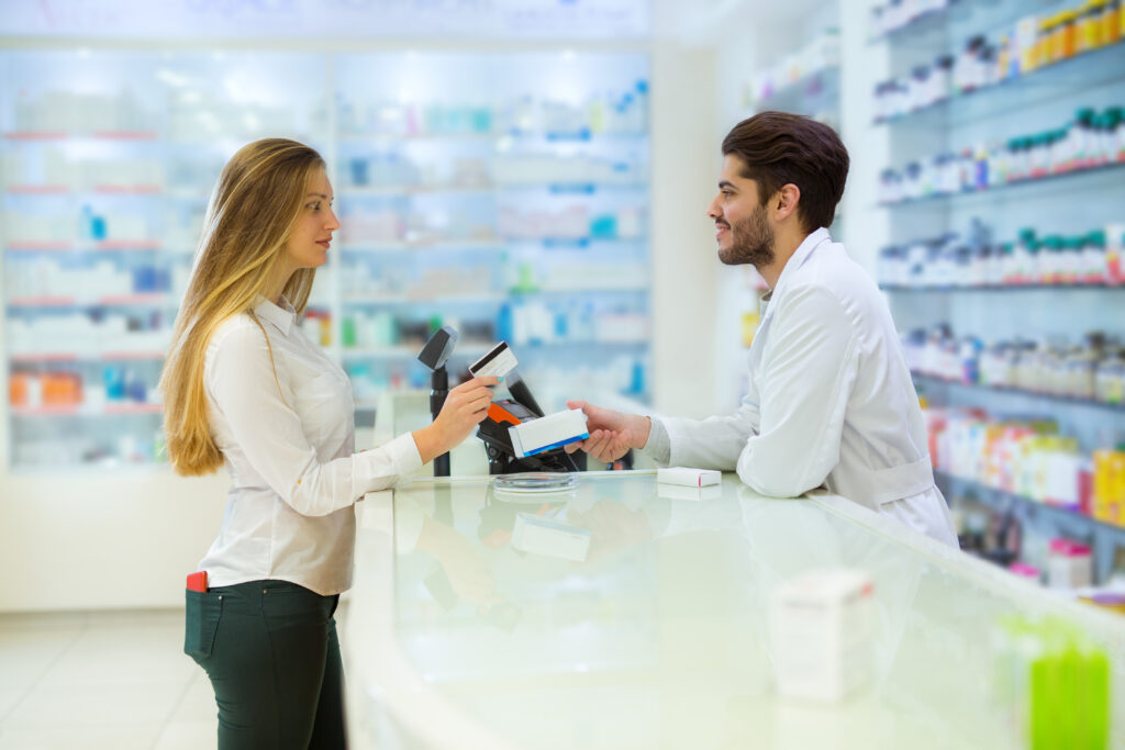 A woman using a credit card to pay at a pharmacy.