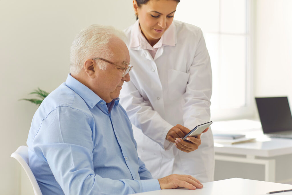 A female doctor teaching a elderly male patient how to use mobile app.