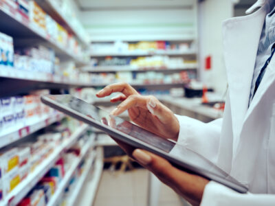 A young female pharmacist checking inventory on a tablet.