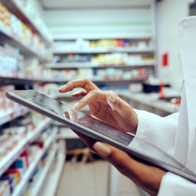 A young female pharmacist checking inventory on a tablet.