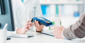 A man using a credit card to pay at a pharmacy.