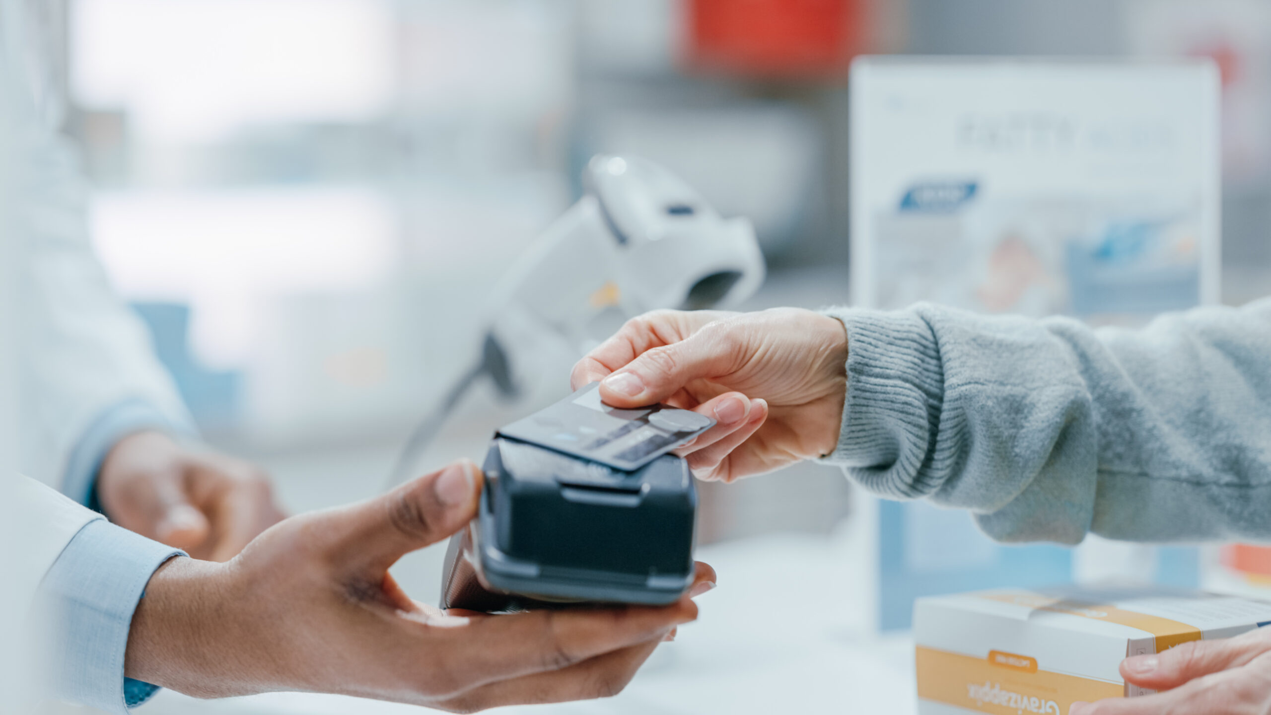 A young woman making a contactless payment at a pharmacy.