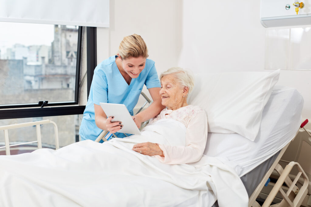 A nurse helping a patient while using a tablet.