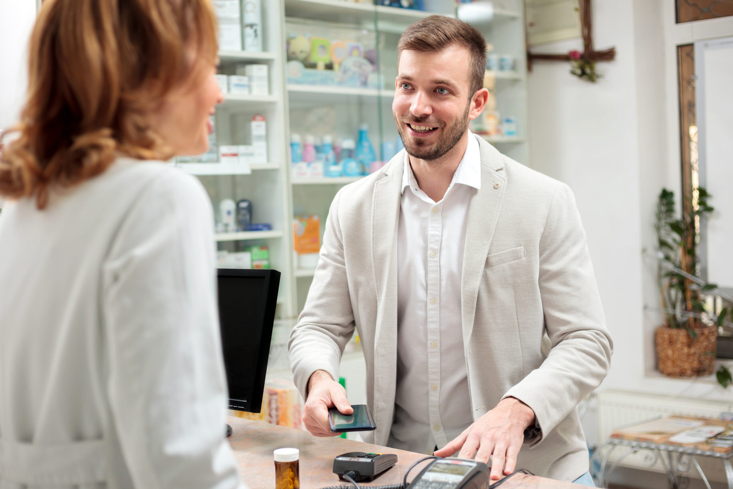 A young men making a contactless payment at a pharmacy.