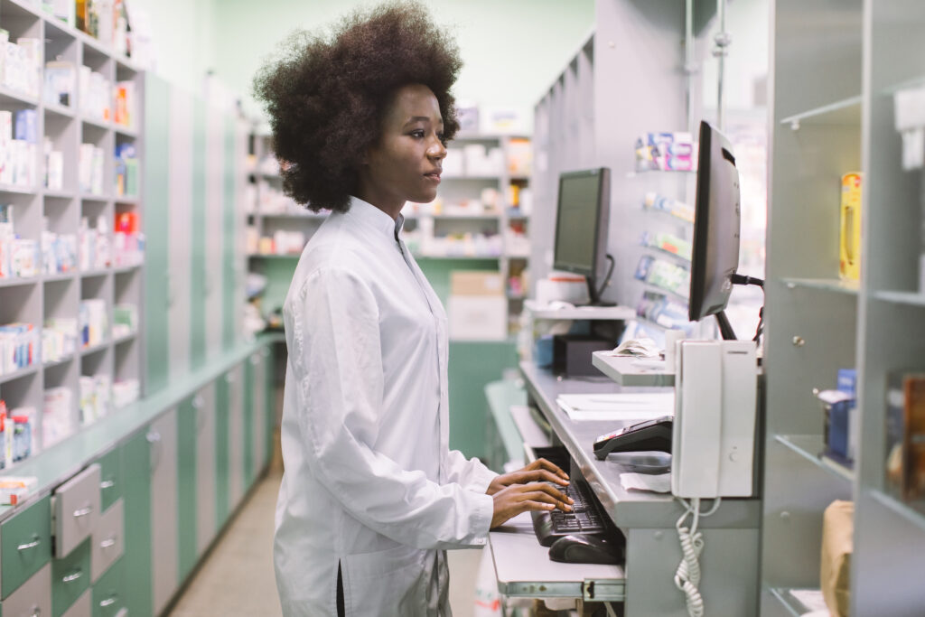 A female pharmacist typing on the computer at the pharmacy.