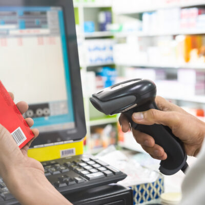 Pharmacist scanning a red medicine box barcode.