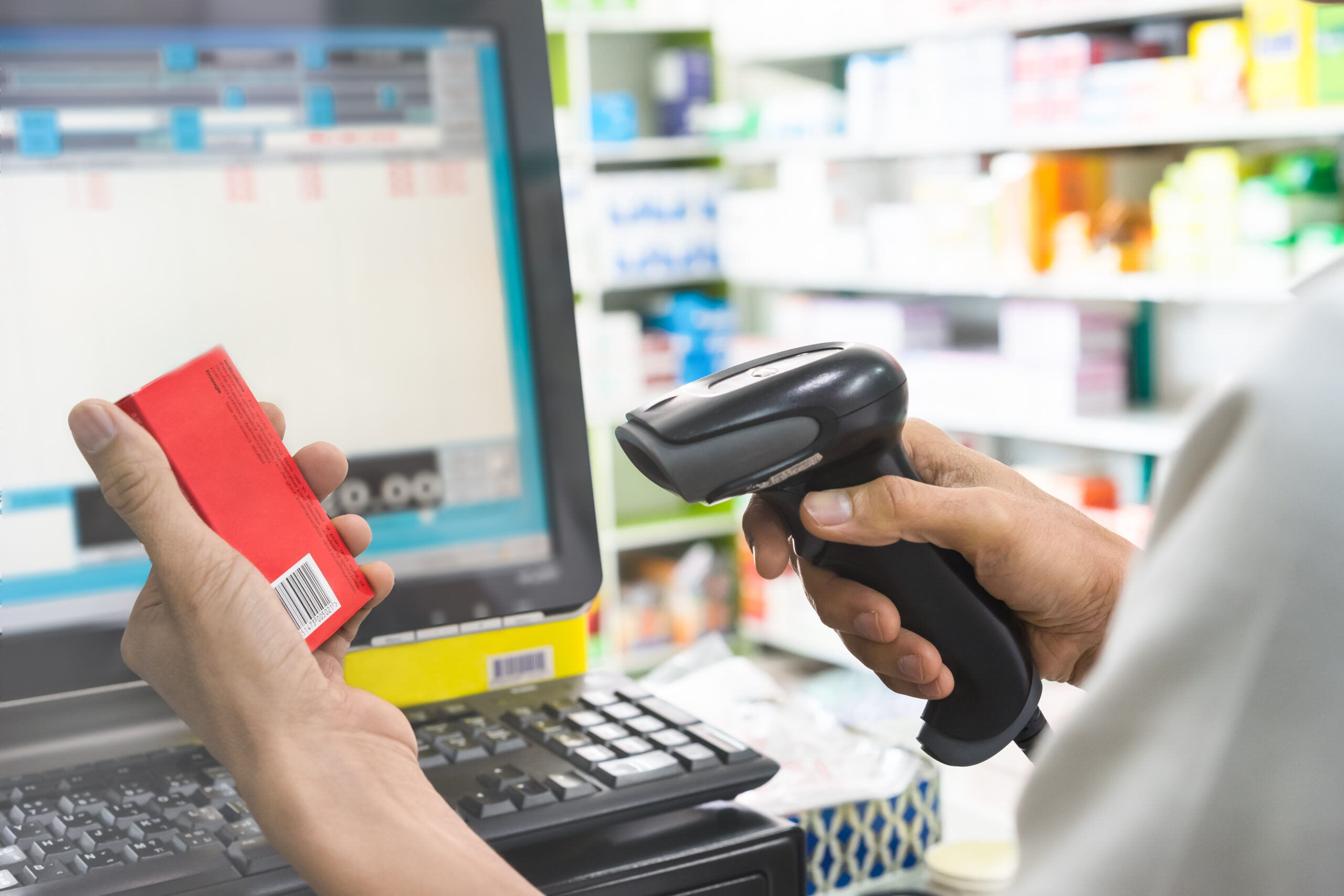 Pharmacist scanning a red medicine box barcode.