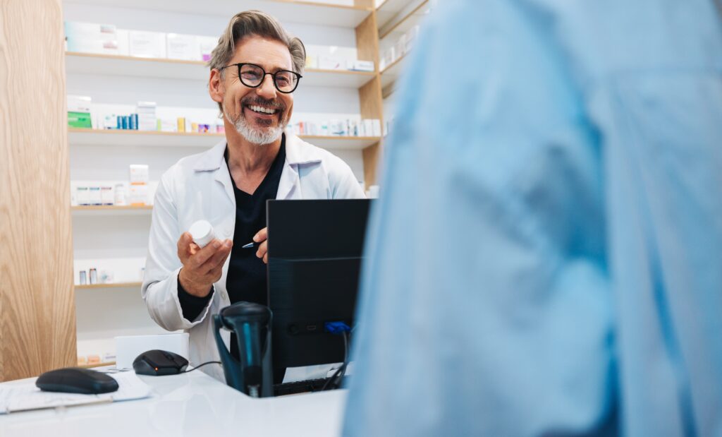 Male pharmacist smiling at a customer at the register.