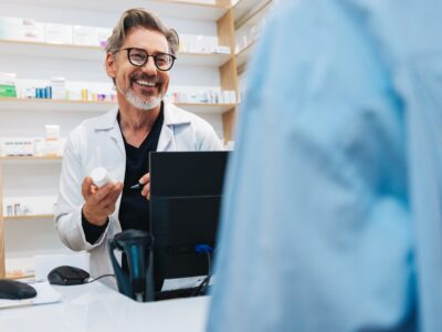 Male pharmacist smiling at a customer at the register.