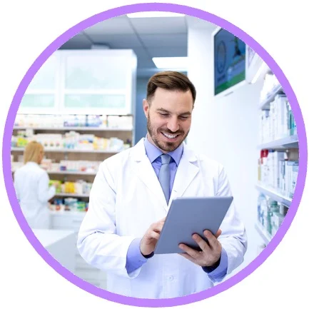 Male pharmacist holding tablet with pharmacy in the background.