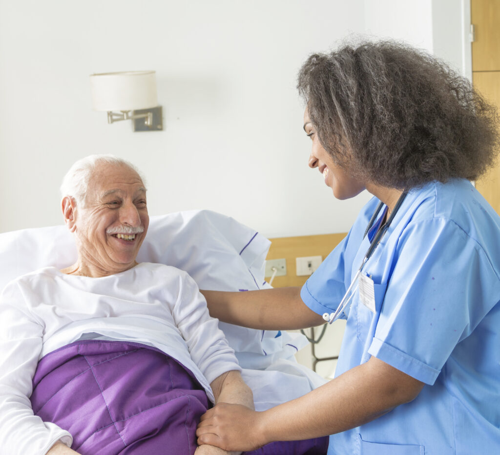 A female doctor visiting an elderly male patient in hospital room.