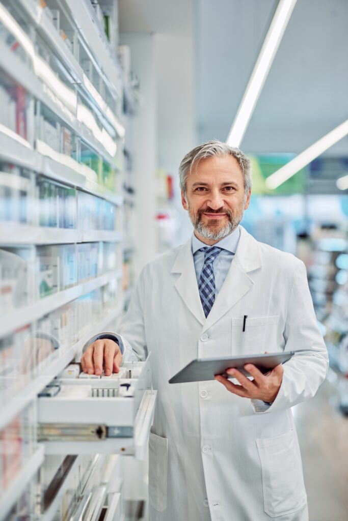 Older white male pharmacist holding tablet