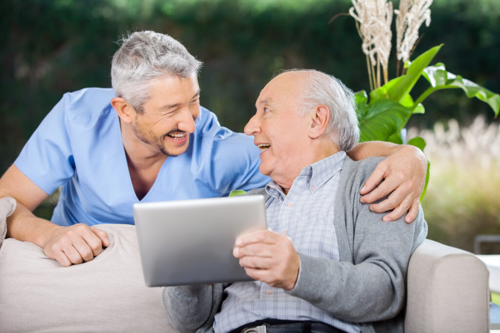 pharmacist smiling with elderly gentleman, looking at ipad