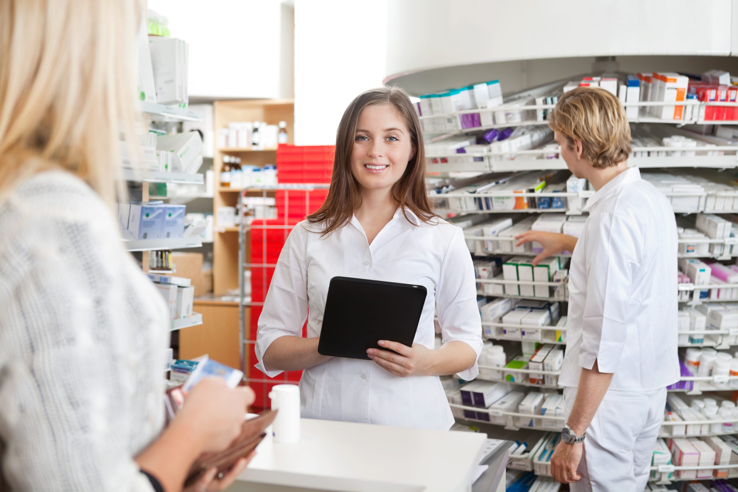 Female pharmacist with tablet at small chain pharmacy